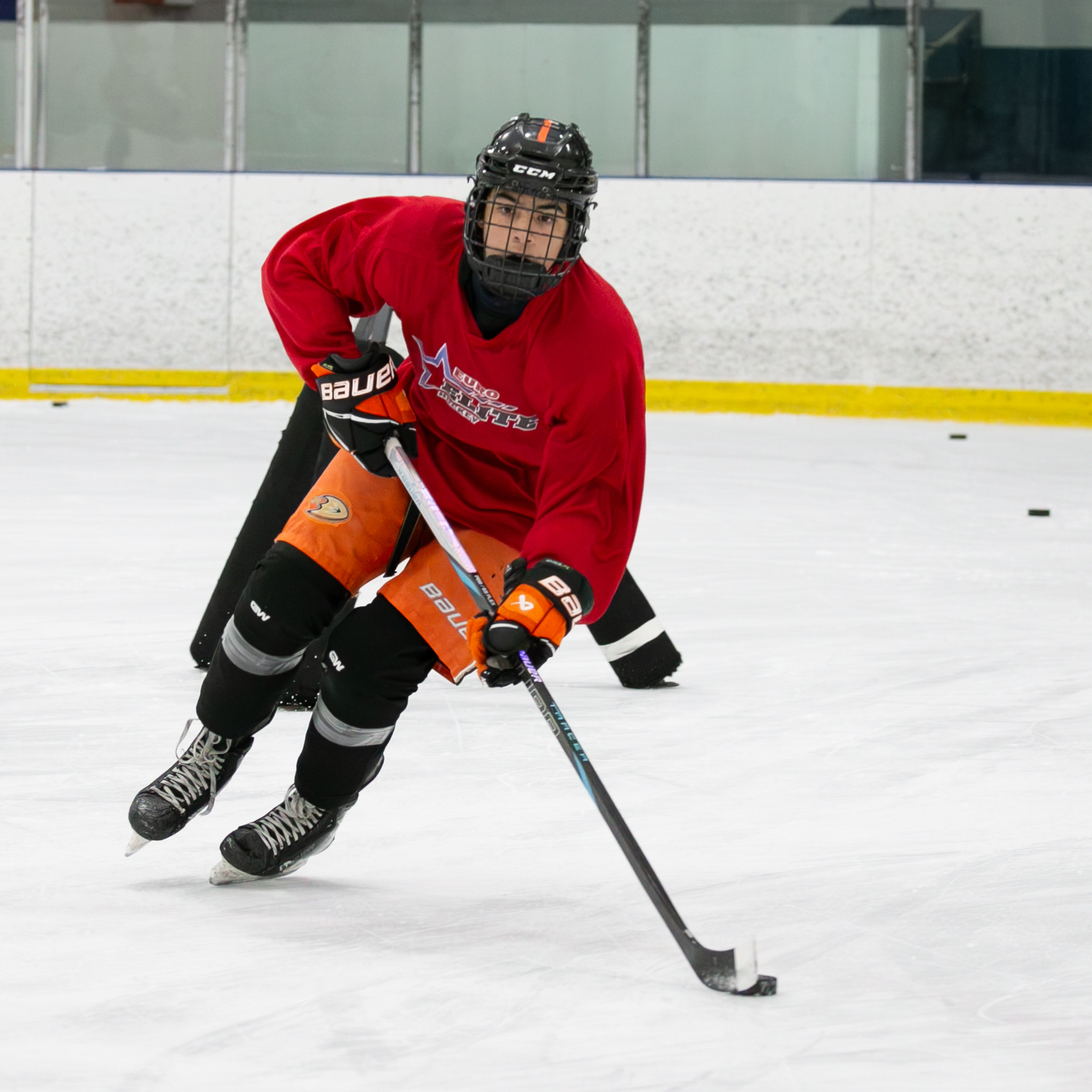 Player in a red Euro Elite Hockey jersey skating with the puck during a skill development session