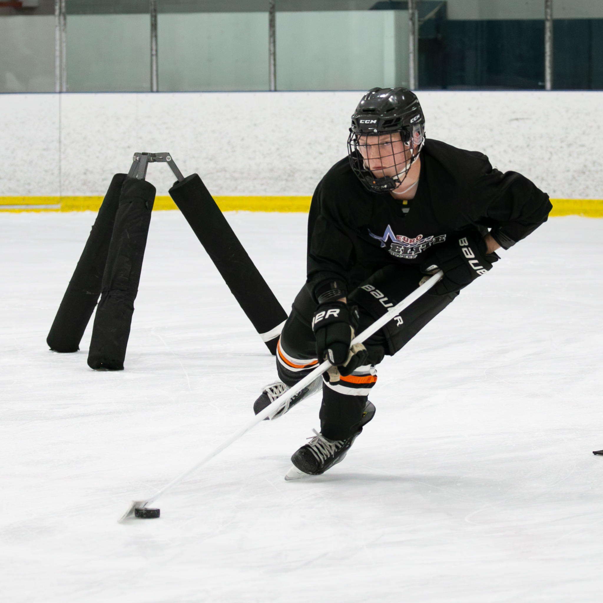 Euro Elite Hockey player in a black jersey practicing puck control and edge work around a training obstacle